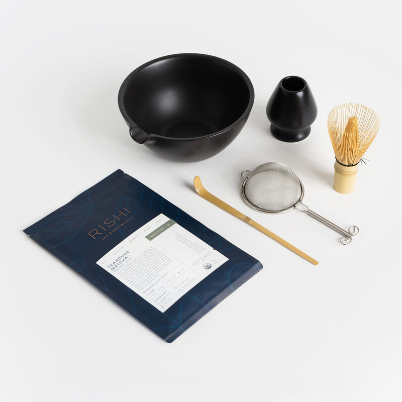 Matcha whisking set with a black pouring bowl, whisk, whisk stand, sifter, scoop and an indigo, resealable bag of Rishi Tea Teahouse Matcha