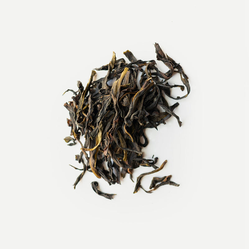 A pile of dried Phoenix Dancong Lan Hua Xiang tea leaves on a white surface by Rishi Tea & Botanicals.