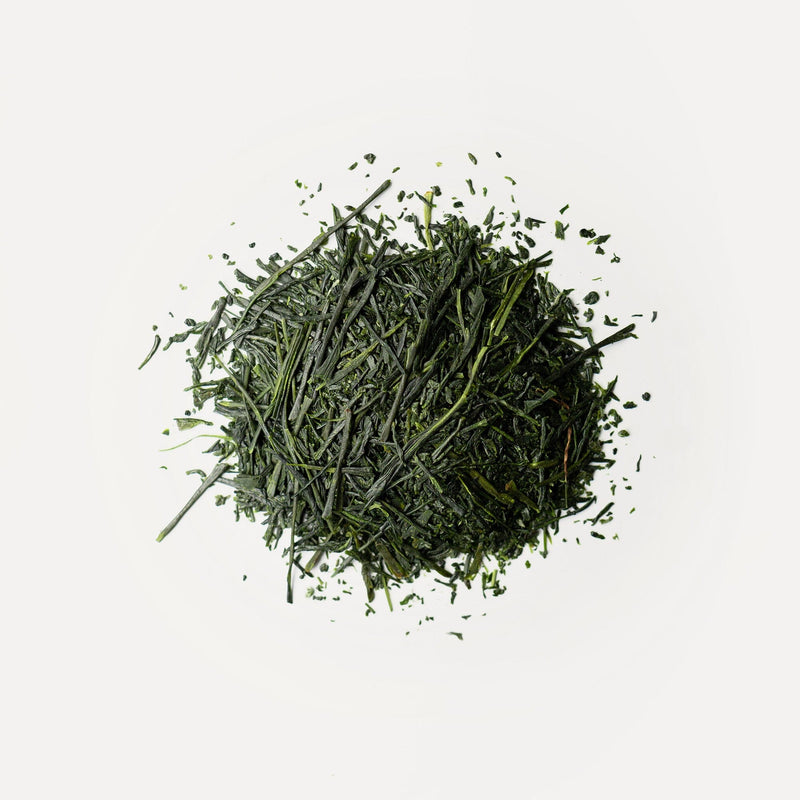 A circular pile of loose, dried Rishi Tea & Botanicals Ryougouchi shincha green tea leaves on a white background, exuding a delicate floral aroma.