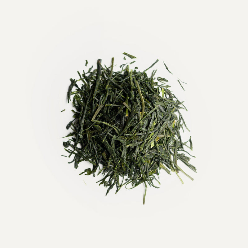 A pile of loose, dried Rishi Tea & Botanicals green tea leaves with a subtle high-mountain aroma rests on a plain white background.