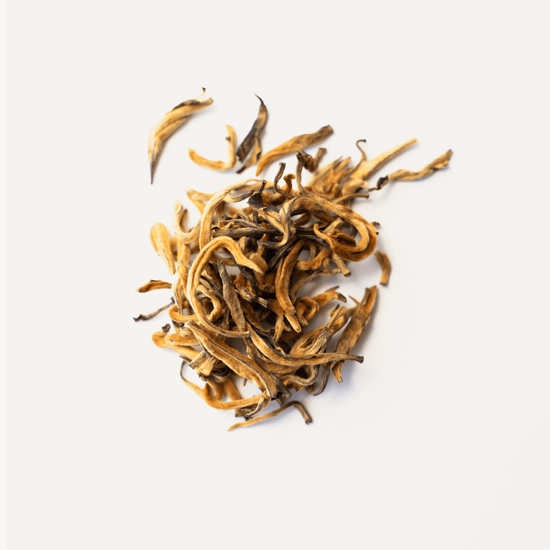 Close-up of Rishi Tea & Botanicals' dried tea leaves on a white background, highlighting the artistry of traditional techniques that enhance their rich aroma.